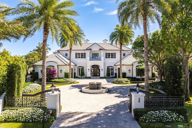 view of front facade featuring decorative driveway, stucco siding, and fence