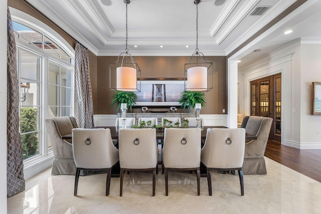 dining space with a tray ceiling, wainscoting, and crown molding