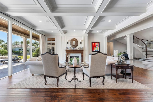 living room featuring wood finished floors, beamed ceiling, decorative columns, and a fireplace