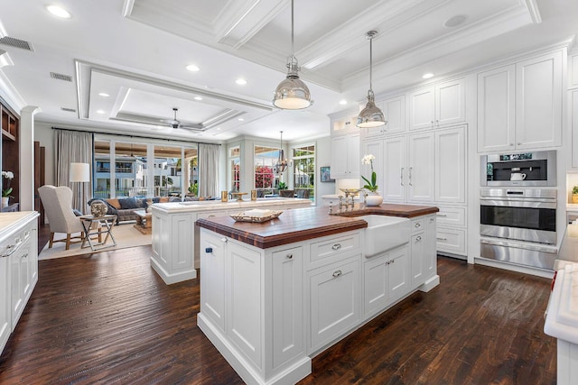 kitchen with a warming drawer, visible vents, a kitchen island, open floor plan, and butcher block counters