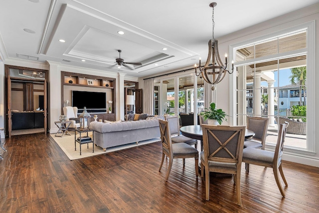 dining area with recessed lighting, dark wood-type flooring, crown molding, ceiling fan with notable chandelier, and a raised ceiling