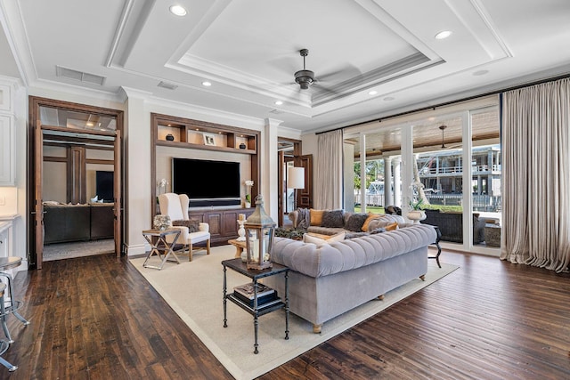 living area featuring visible vents, ornamental molding, a tray ceiling, dark wood-style floors, and ceiling fan