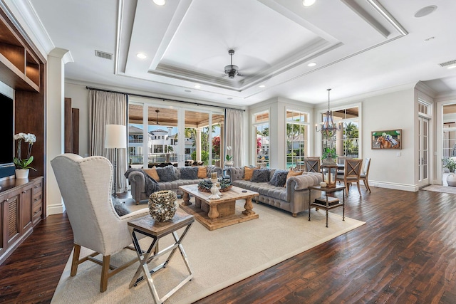 living area with visible vents, crown molding, dark wood-type flooring, and a tray ceiling