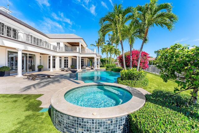 view of pool featuring a patio, fence, a lawn, and a pool with connected hot tub