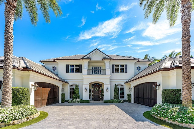 view of front facade featuring an attached garage, decorative driveway, and a balcony