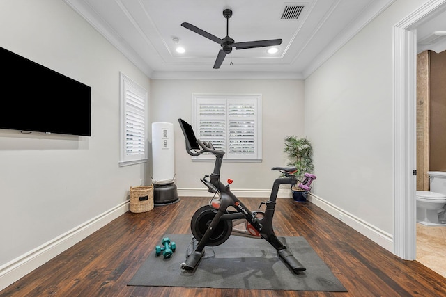 exercise area with a ceiling fan, a tray ceiling, wood finished floors, crown molding, and baseboards