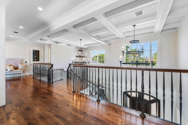 hallway with hardwood / wood-style flooring, an upstairs landing, coffered ceiling, and a chandelier