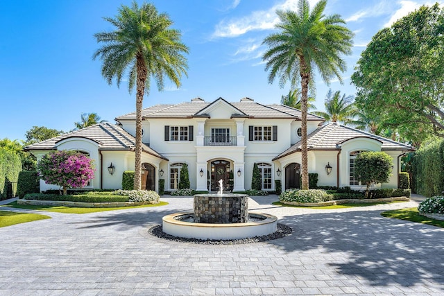 view of front facade featuring curved driveway, a tile roof, and stucco siding