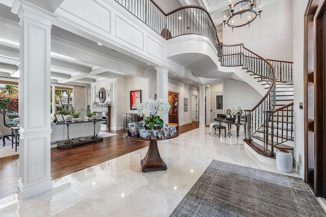 entryway with stairway, a towering ceiling, marble finish floor, coffered ceiling, and ornate columns