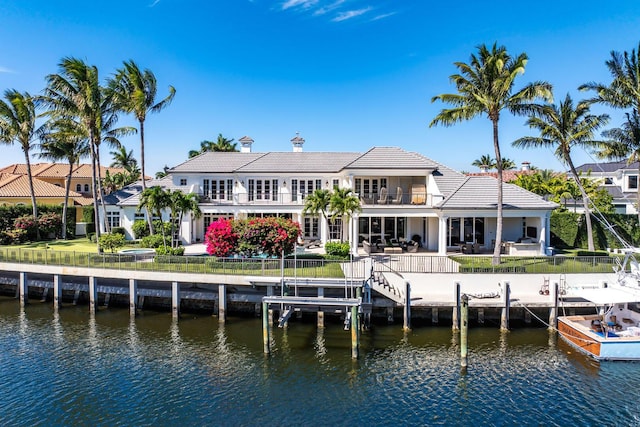 back of property with a balcony, a patio area, a water view, and a fenced backyard