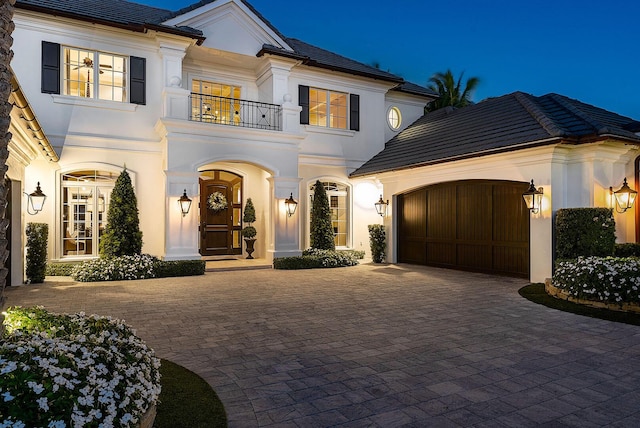 view of front of property with stucco siding, decorative driveway, a balcony, and an attached garage