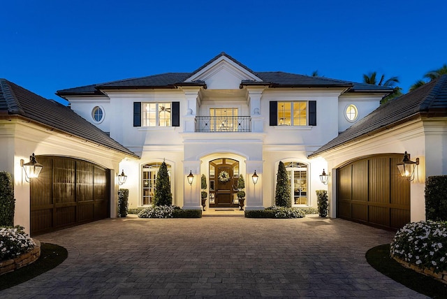 view of front of property with decorative driveway, a balcony, and stucco siding