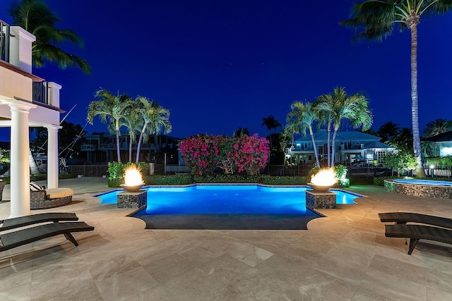 pool at twilight featuring a patio, a fenced in pool, a fenced backyard, and an in ground hot tub