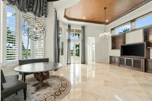 interior space with a tray ceiling, marble finish floor, a notable chandelier, a high ceiling, and baseboards