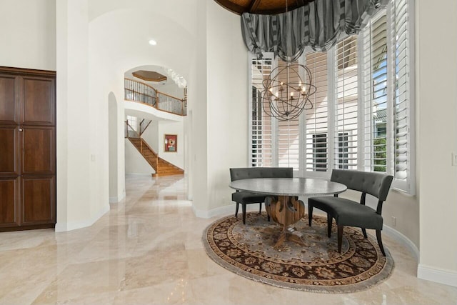 dining room featuring marble finish floor, a high ceiling, and stairs