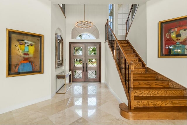 entrance foyer featuring french doors, marble finish floor, stairway, an inviting chandelier, and baseboards