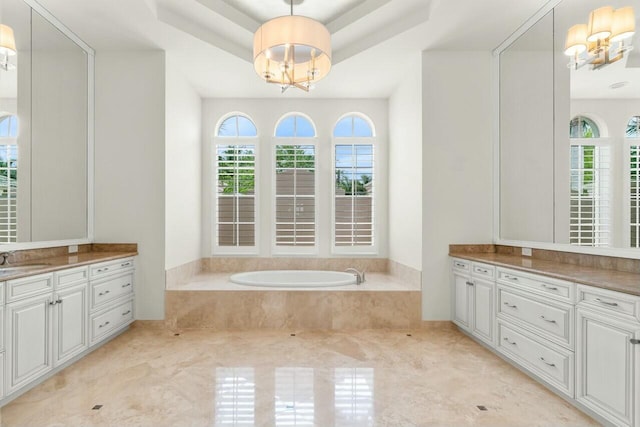 bathroom with plenty of natural light, a tray ceiling, a notable chandelier, and vanity