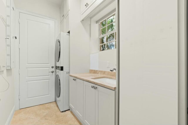 laundry room with stacked washing maching and dryer, a sink, and cabinet space