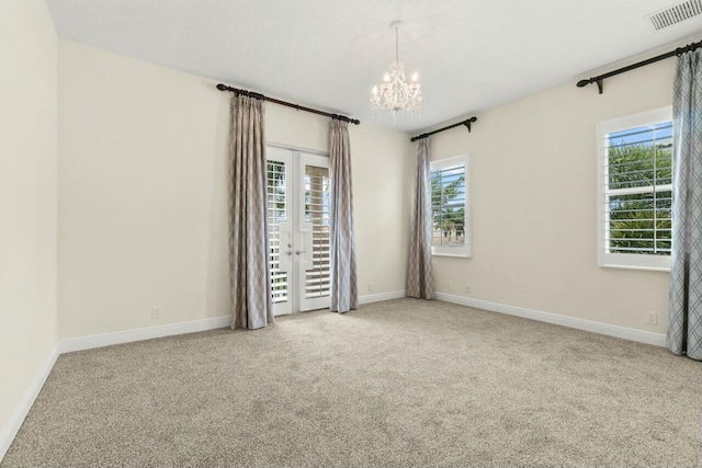 spare room featuring carpet, french doors, visible vents, a chandelier, and baseboards