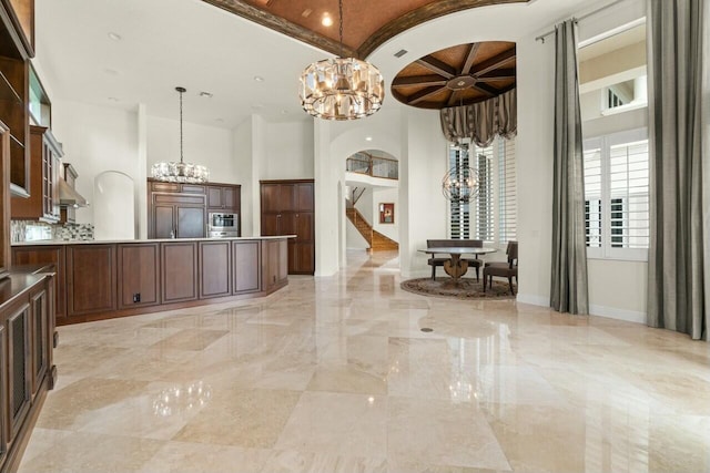 kitchen featuring arched walkways, baseboards, marble finish floor, paneled refrigerator, and a notable chandelier