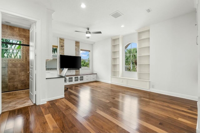 unfurnished living room with hardwood / wood-style floors, plenty of natural light, a ceiling fan, and baseboards