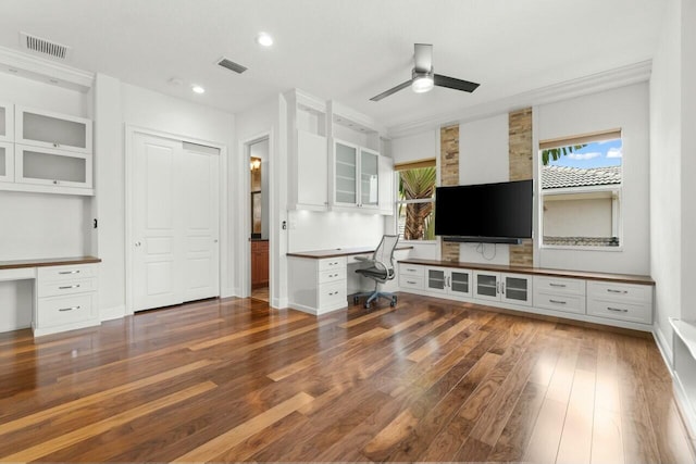 unfurnished office with a ceiling fan, built in study area, visible vents, and hardwood / wood-style flooring