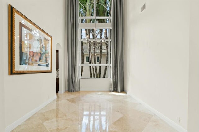 interior space featuring marble finish floor, baseboards, visible vents, and arched walkways