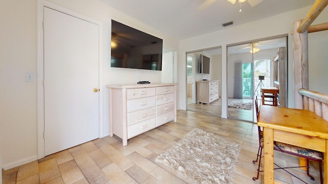 bedroom featuring a ceiling fan, visible vents, and multiple closets