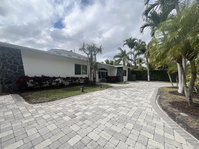 rear view of house with fence, decorative driveway, and stucco siding