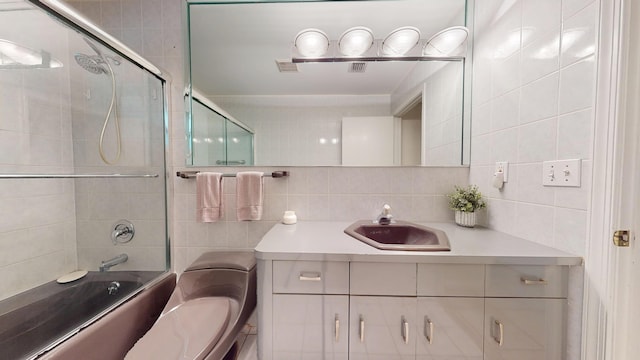 bathroom with tasteful backsplash, bath / shower combo with glass door, tile walls, and vanity