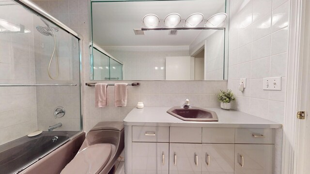 ensuite bathroom featuring connected bathroom, a shower with shower door, vanity, tile walls, and tile patterned floors