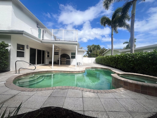 view of swimming pool with a patio, a pool with connected hot tub, a ceiling fan, fence, and exterior kitchen