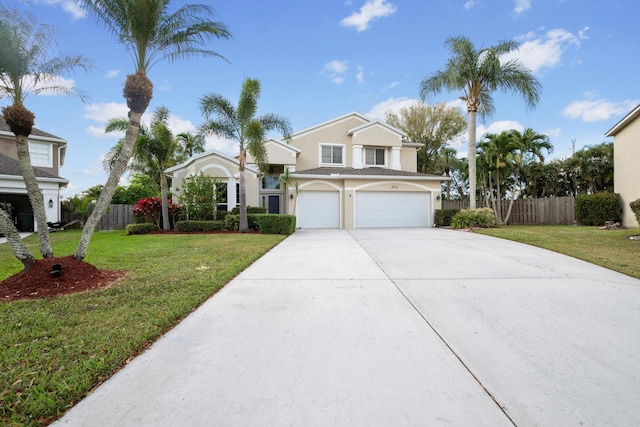 view of front facade with an attached garage, driveway, a front yard, and fence