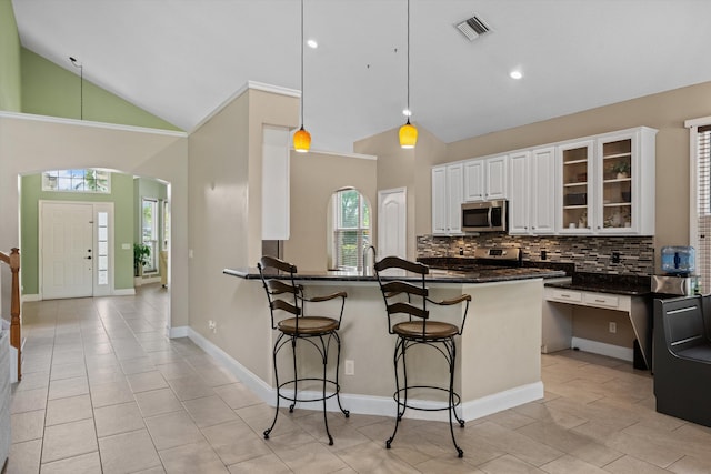 kitchen with stainless steel appliances, tasteful backsplash, a kitchen breakfast bar, light tile patterned floors, and high vaulted ceiling