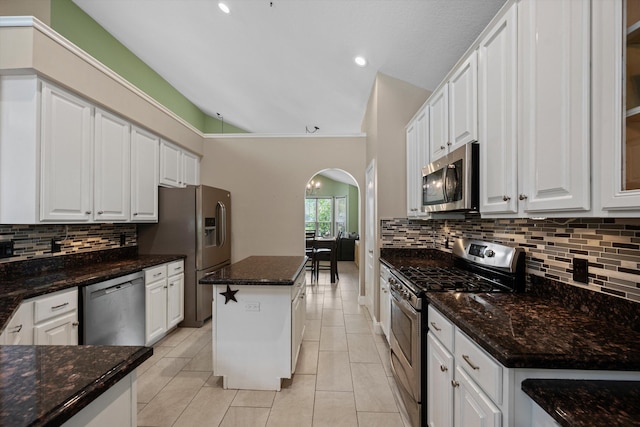 kitchen featuring appliances with stainless steel finishes, arched walkways, white cabinets, decorative backsplash, and recessed lighting