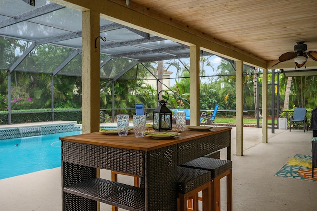 outdoor pool featuring ceiling fan, a patio, and glass enclosure