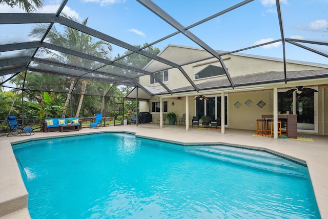 outdoor pool featuring an outdoor hangout area, ceiling fan, a patio area, and glass enclosure