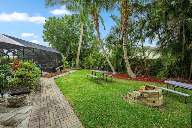 view of grassy yard featuring an outdoor fire pit and a lanai