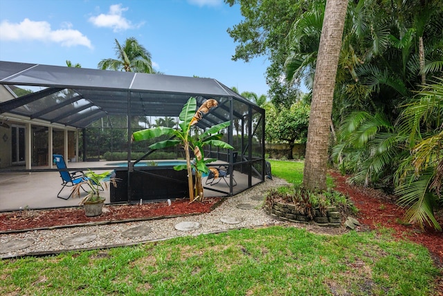view of grassy yard featuring an outdoor pool, glass enclosure, and a patio
