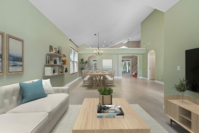 living room featuring arched walkways, high vaulted ceiling, a chandelier, plenty of natural light, and baseboards