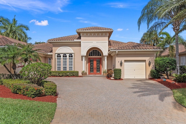 mediterranean / spanish house featuring a garage, french doors, a tiled roof, and stucco siding