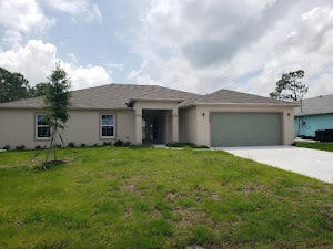 single story home featuring concrete driveway, a front lawn, and an attached garage