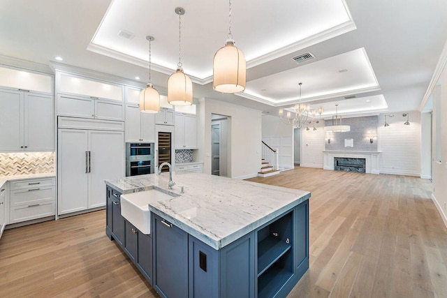 kitchen featuring visible vents, paneled fridge, a tray ceiling, and a sink