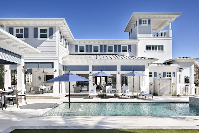 rear view of house featuring metal roof, a patio, a gate, an outdoor pool, and a standing seam roof