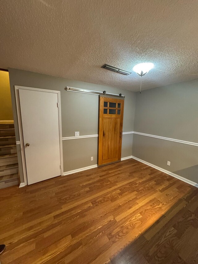 1458 N Lawnwood Cir Unit 23A, Fort Pierce, FL 34950 - spare room with wood finished floors, a textured ceiling, a barn door, baseboards, and stairs