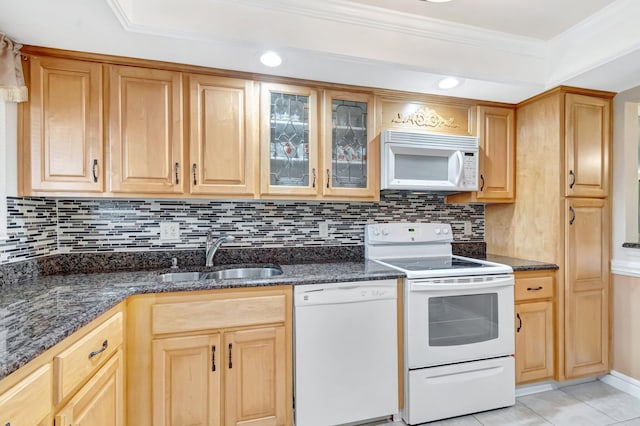 kitchen featuring white appliances, light tile patterned floors, ornamental molding, dark stone countertops, and a sink