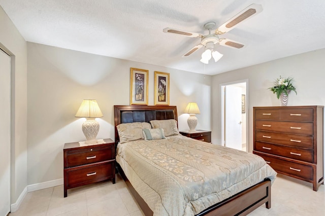 bedroom with light tile patterned floors, a textured ceiling, a ceiling fan, and baseboards