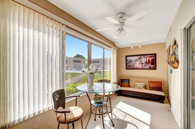 sunroom featuring rail lighting and a ceiling fan