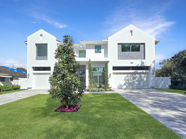 modern farmhouse style home featuring a garage, a front lawn, decorative driveway, and stucco siding