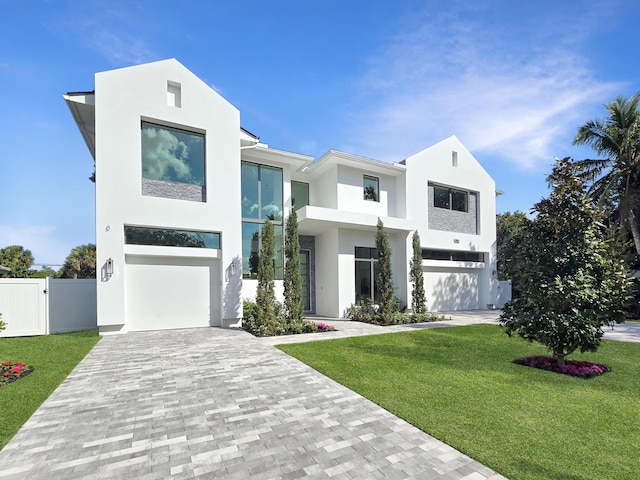 view of front facade with a garage, stucco siding, fence, decorative driveway, and a front yard